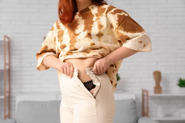 Image of woman trying to do her trousers up after pregnancy weight gain Lyndhurst